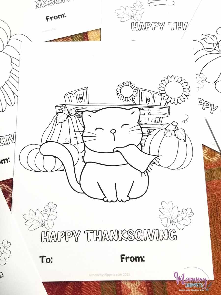 Thanksgiving card printable for kids to color-features the image of a Fall cat smiling, in front of pumpkins